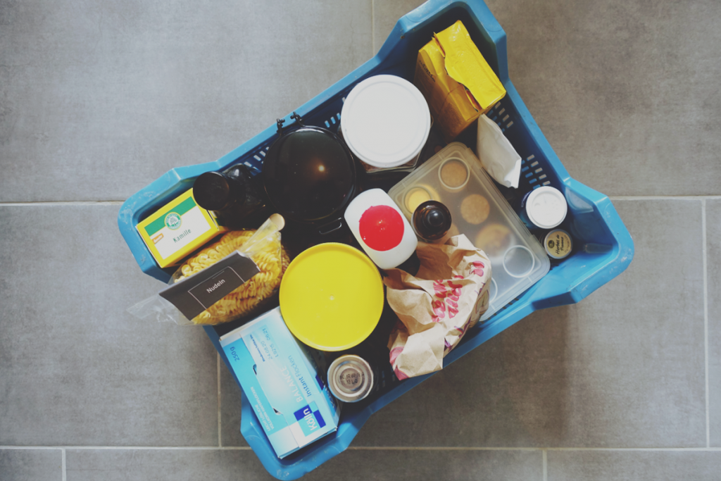 Beitragsbild // Lowwaste im Urlaub // Das Bild zeigt eine gepackte Kiste mit Lebensmitteln, verpackt und teilweise auch OVP mit und ohne Plastikpackungen.
